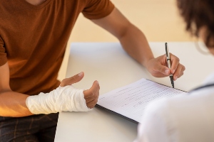 Someone with a injured wrist signing a document. 