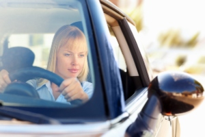 A woman checking rear view mirror.