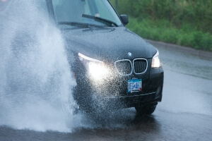 A car riding fast through a puddle creating a wave.