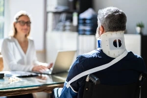 image of a female attorney facing a male in a wheelchair. Image shows a back view of the injured man.