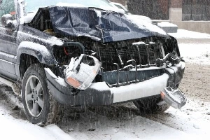 image shows smashed-in front end of a black SUV in snow