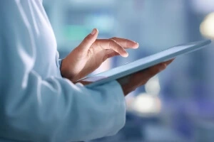 close up image of a medical professional's hand looking at an electronic chart