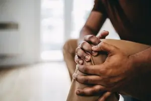 Close up of young black man's holding injured knee. You do not see the man's face.